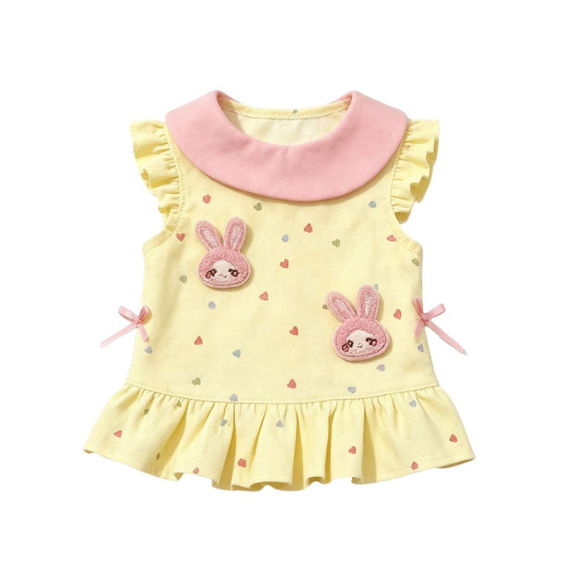 A yellow sleeveless dog dress with a pink Peter Pan collar, decorated with two pink bunny patches, small heart prints, and pink ribbon bows on the sides.